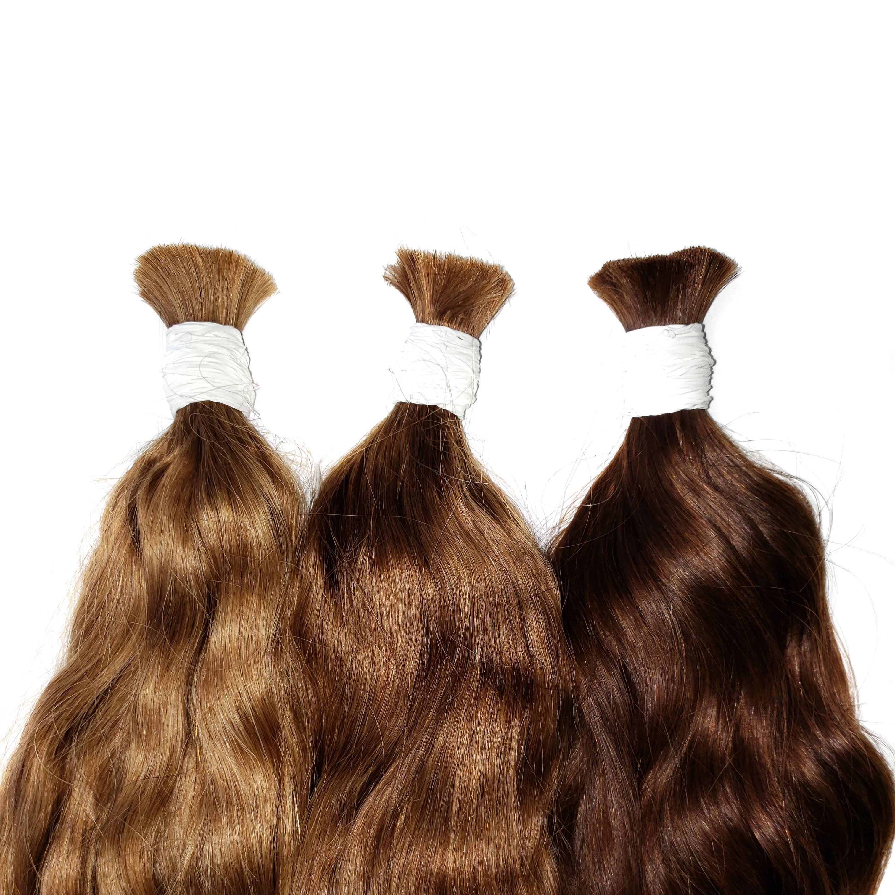 Wavy hair bundles wrapped in a white band. Natural wavy hair. Light brown, medium brown, dark brown hair bundles.